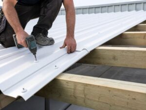 Roofer fastening white corrugated PVC roofing sheets with sealing washers