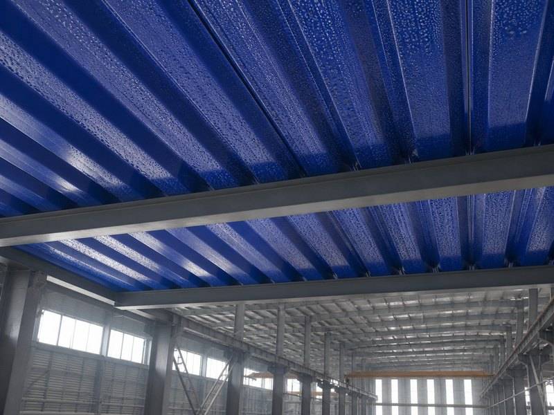 Condensation droplets beneath blue corrugated roofing sheets in an industrial building
