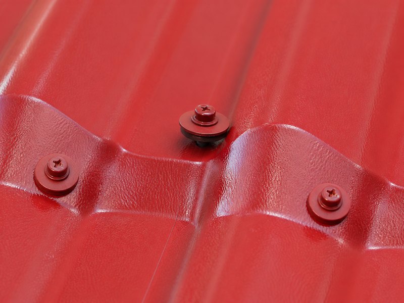 Raised roofing screw and washer above a red synthetic resin roofing profile