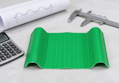 Green corrugated PVC roofing sheet sample with a caliper, drawing and calculator