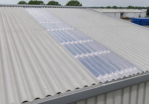Clear corrugated rooflight strip integrated into a pale grey plastic warehouse roof